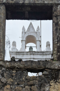 Torre sineira enquadrada entre ruínas